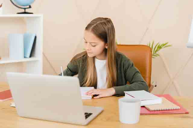 白种人小女生做家庭作业，在笔记本电脑上远程学习，在家远程准备考试。.jpg